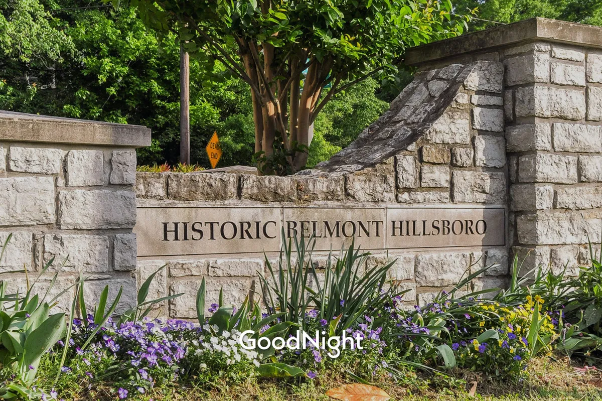 The image features a stone entrance sign surrounded by lush greenery and vibrant flowers, embodying the vibe of a well-maintained neighborhood park or green space.
