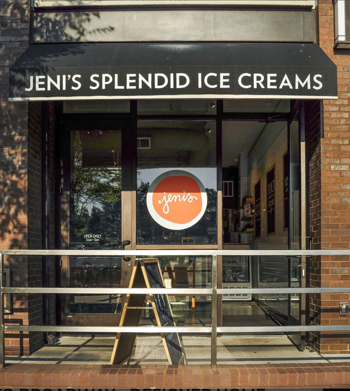 The exterior of Jeni’s Splendid ice cream shop, featuring a cheerful storefront sign, welcoming doorway, and a visible menu board. The scene captures a bright, energetic mood with people gathering to enjoy sweet treats.