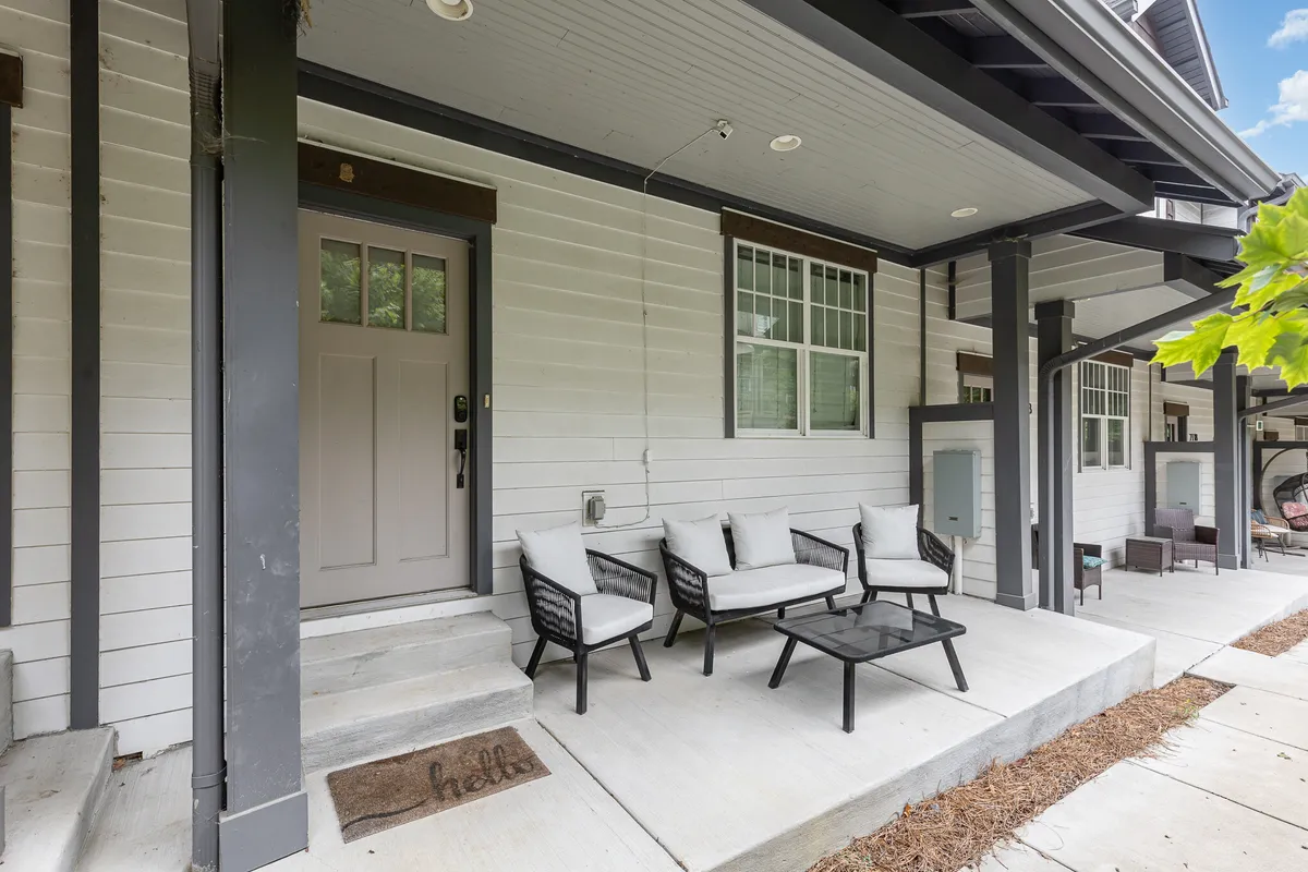 The image shows the front door of the home, surrounded by a welcoming seating area and a coffee table, with a visible welcome mat. The space feels inviting and transitions seamlessly between indoor comfort and the Nashville neighborhood outside.