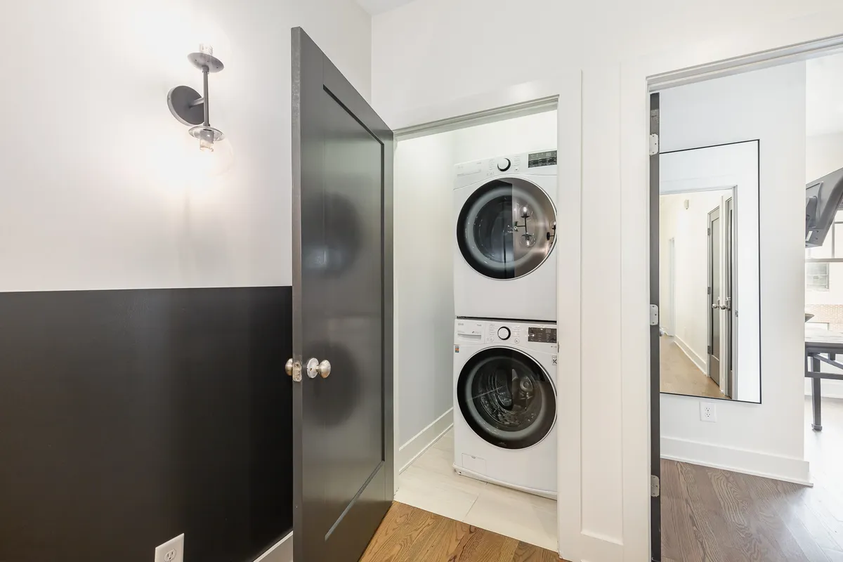A practical laundry area with a washer and dryer, a black door, and a simple light fixture. The space is organized and ready for guests to handle laundry needs with ease.